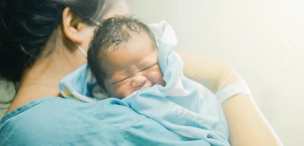 Một người mẹ đang âu yếm vỗ về em bé sơ sinh của mình trong bệnh viện