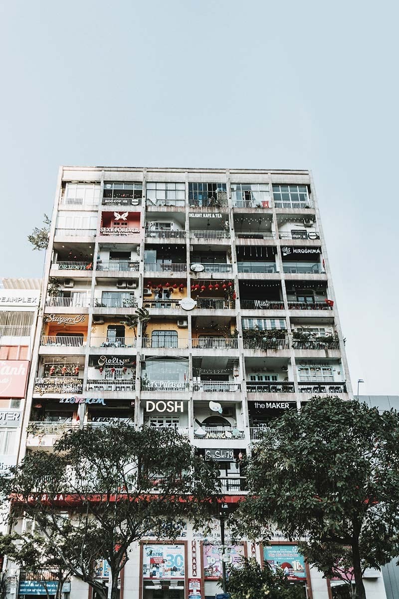 Khám phá 5 Con Đường Thời Trang Sài Gòn Nổi Bật Dành Cho Tín Đồ Mua Sắm 10 Toàn cảnh chung cư cũ nhìn từ phía ngoài với ban công đầy cây xanh và cửa hàng