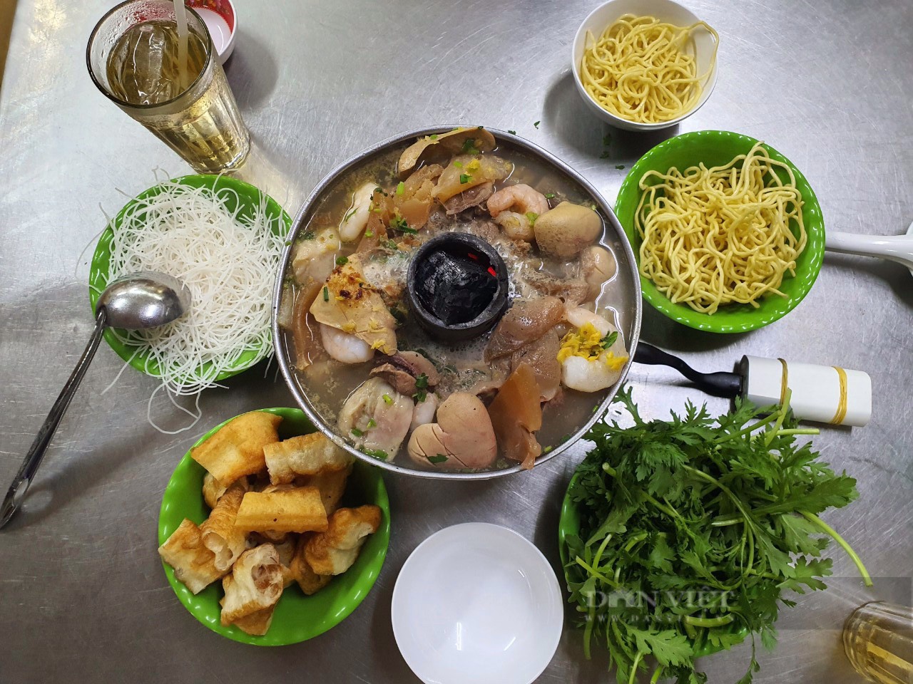 Nồi lẩu cù lao truyền thống của quán lẩu cá Dân Ích với than đỏ lửa và quạt mini