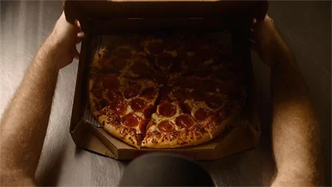 Một nhóm nhân viên Pizza Hut với nụ cười thân thiện đang làm việc và giao tiếp vui vẻ trong bếp